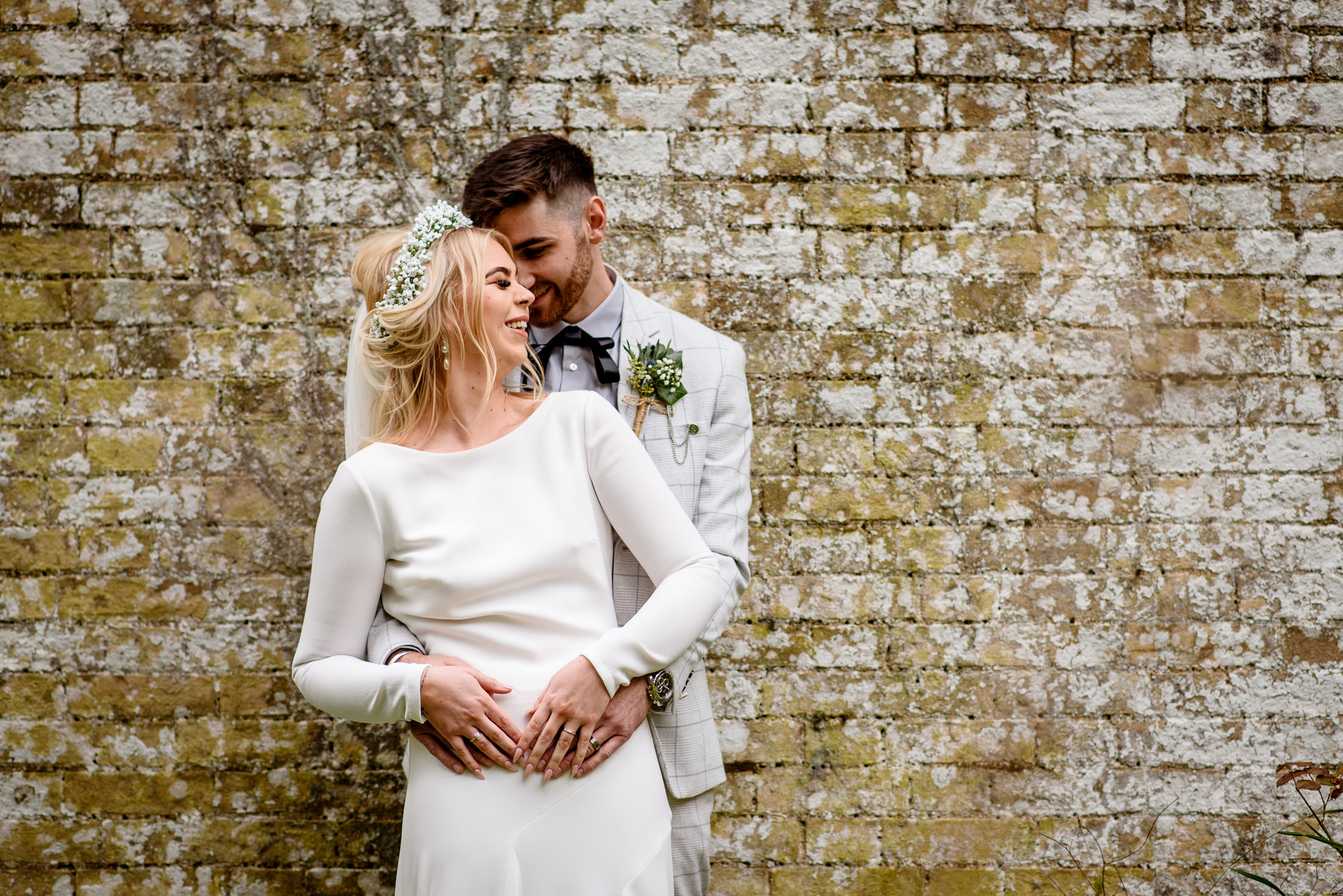 A bride and groom embracing in front of a scrivelsby walled garden.
