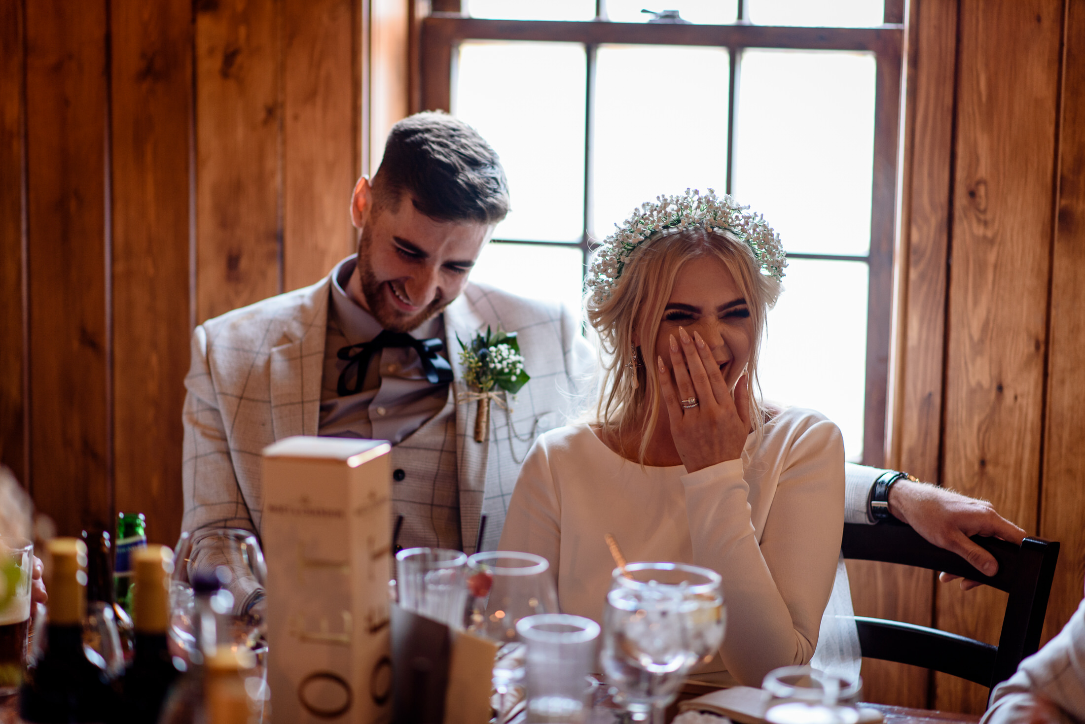 A wedding couple laughing at a table set in the picturesque Scrivelsby Walled Garden.