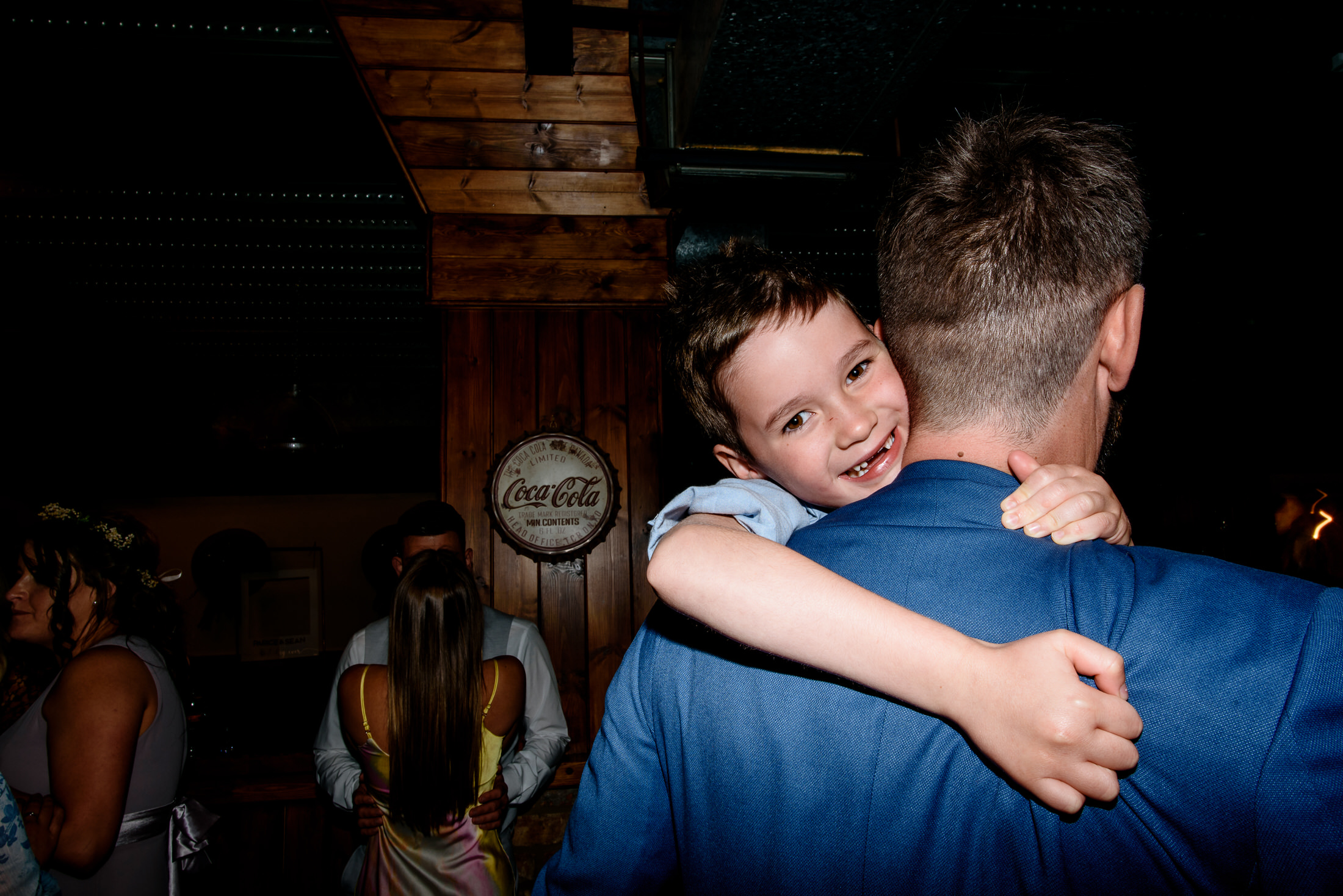 A man hugging a young boy at a wedding party.