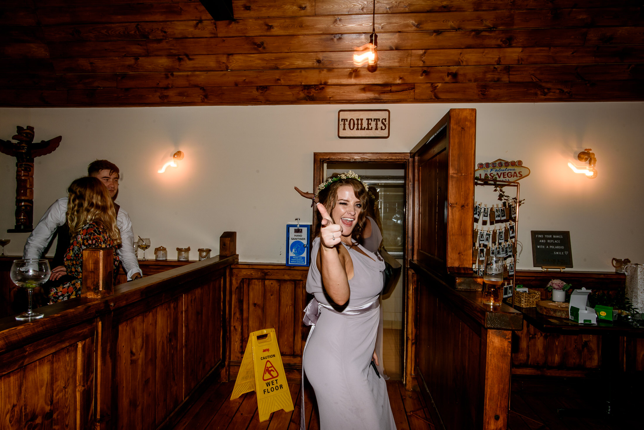 A woman in a wedding dress is posing for a picture in a bar.