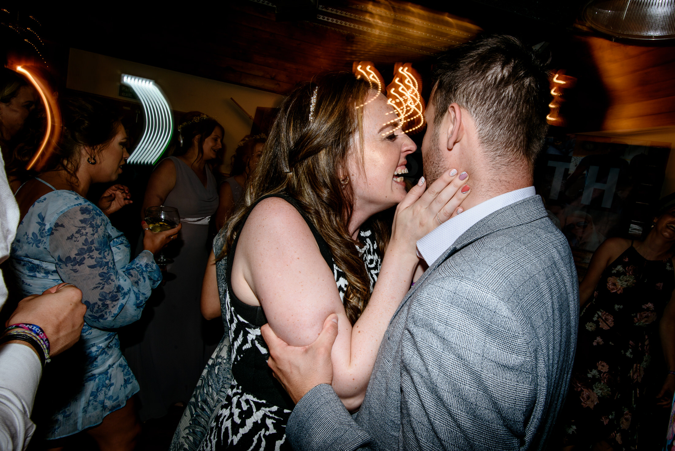 A couple embracing and sharing a passionate kiss on the dance floor at a wedding party.